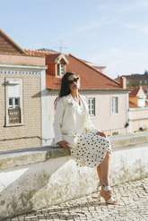a lady in a white vest, a white blazer and a white skirt with black polka dots